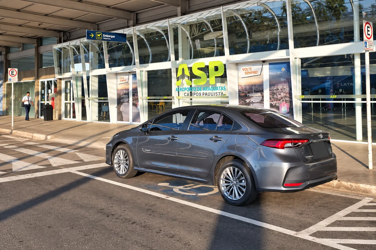 Toyota Corolla cinza da Rose Transportes em área de embarque, com placa protegida